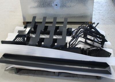 A pallet of small, incritate components that have been laser cut, cnc folded, welded and powder coated black.