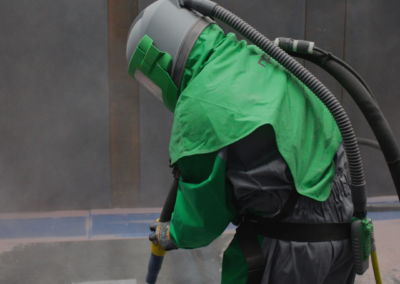 A Bromarc employee sandblasting a component in the blast shed.